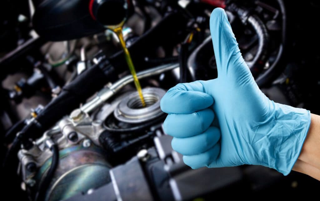 Hand in nitrile glove giving thumbs up during oil change.
